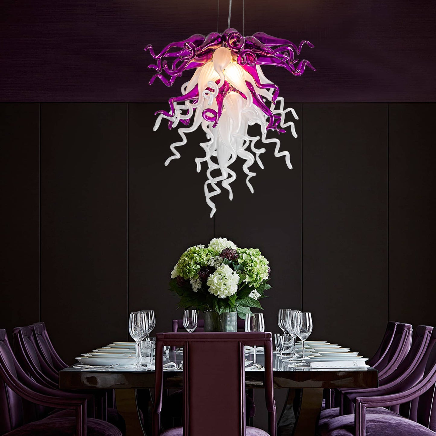 Modern dining table setting with a unique purple and white chandelier against a dark wall.