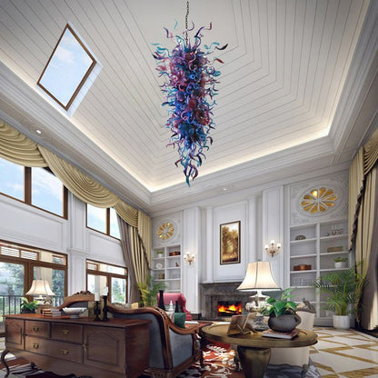 Grand luxury living room with vaulted ceilings and a classic fireplace, illuminated by a massive blue and purple artisan glass chandelier.