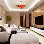 Luxury high-ceiling living space with neutral tones highlighting the warm glow of an autumn-themed artisan glass chandelier.