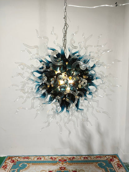 Artisan blue and clear glass starburst chandelier hanging against a minimalist white wall in a bright studio gallery