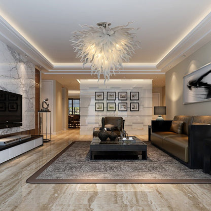 Luxury modern living room featuring a white sculptural glass chandelier centered above a dark coffee table and neutral furnishings.