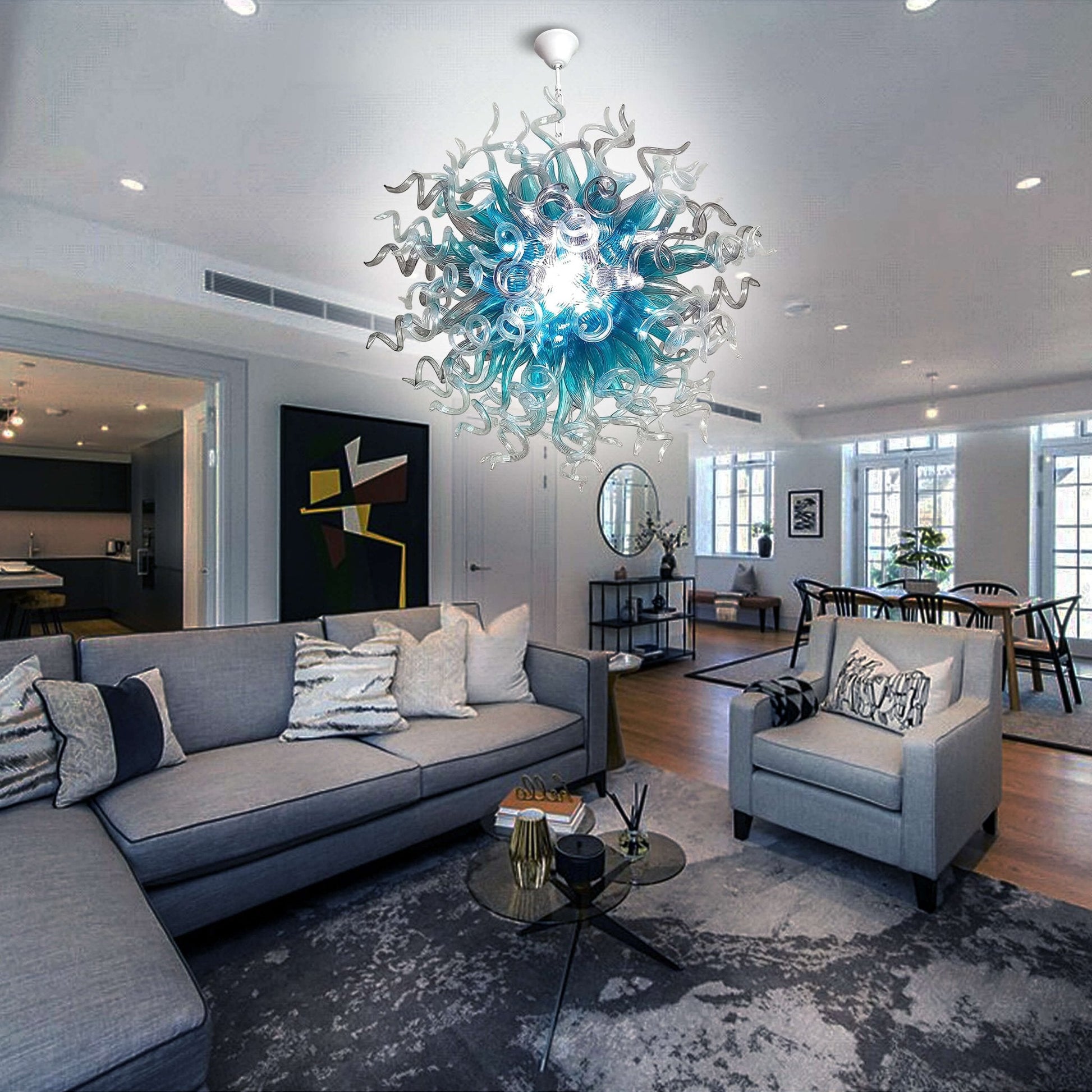 Spacious contemporary living room with gray furniture and a large blue blown glass art chandelier hanging in the center.
