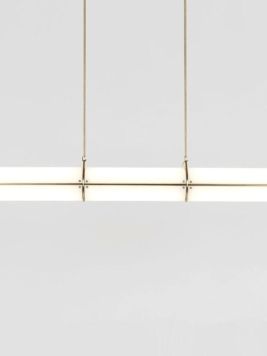 Modern white frosted glass cylinder pendant light with gold brass hardware detail view.