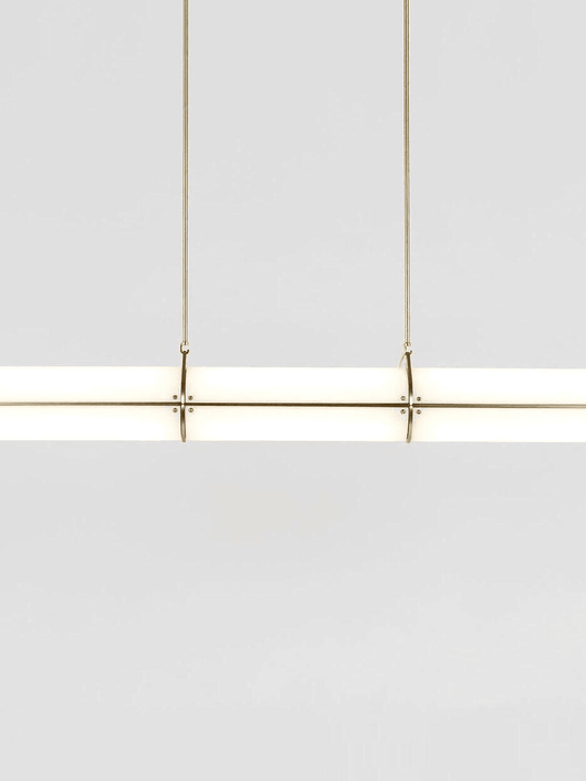 Modern white frosted glass cylinder pendant light with gold brass hardware detail view.