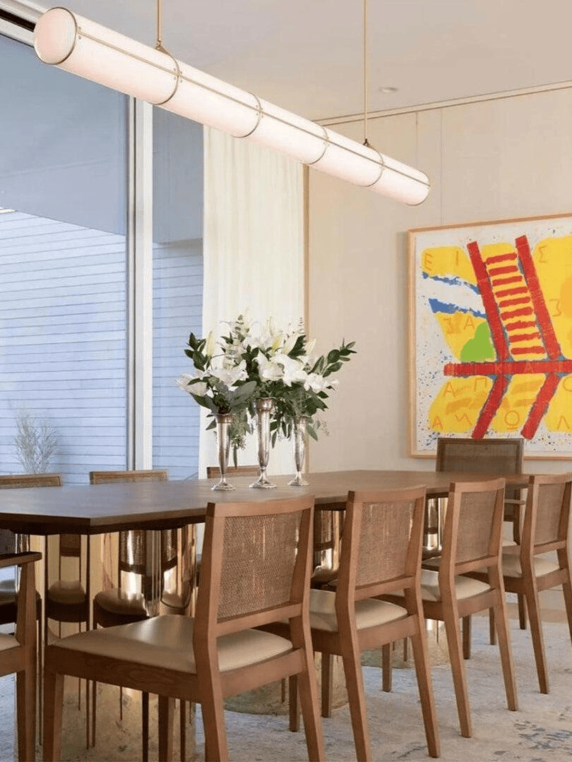 Elegant dining room decor with a large wooden table and a matching horizontal glass cylinder chandelier.