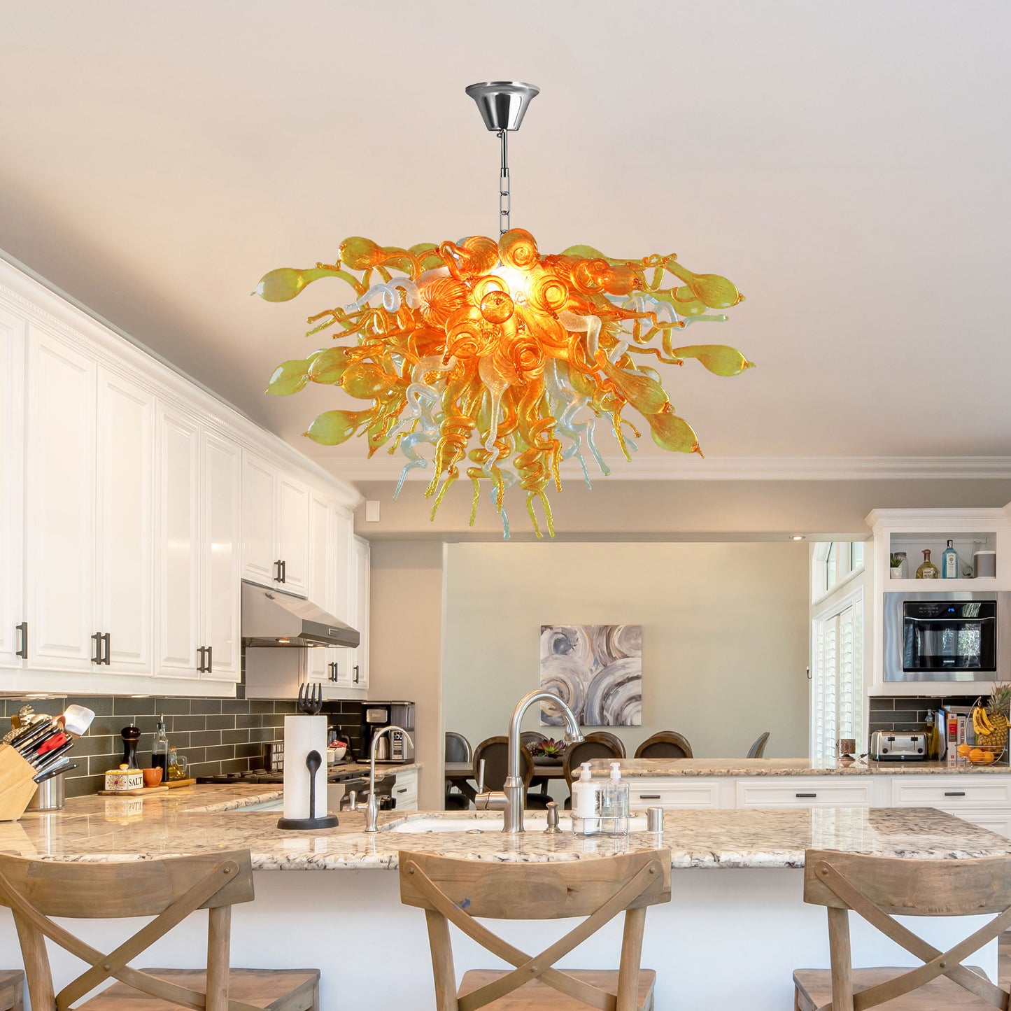 Large hand blown glass light fixtures suspended over a bright white kitchen island with granite countertops.