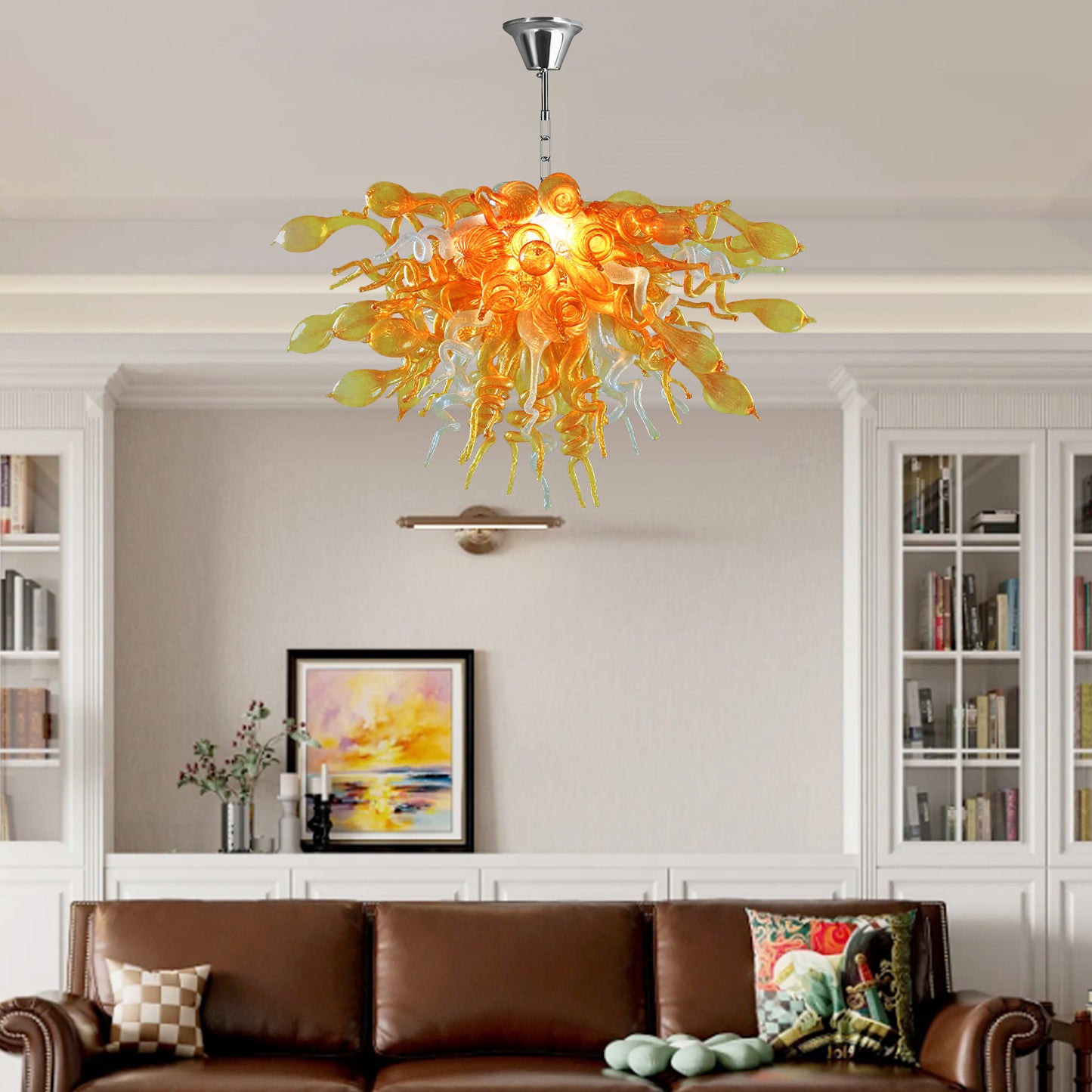 Modern hand blown art glass chandelier illuminating a cozy living room with a brown leather sofa.
