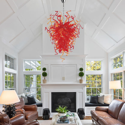 Red sculptural hand blown glass chandelier centered above a white fireplace in a modern white living room.