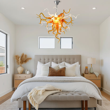 A Chihuly-style amber hand blown glass chandelier in a rustic bedroom.