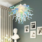 Chihuly Colorful chandelier hanging in a room with a gray wall, white curtains, and framed pictures.