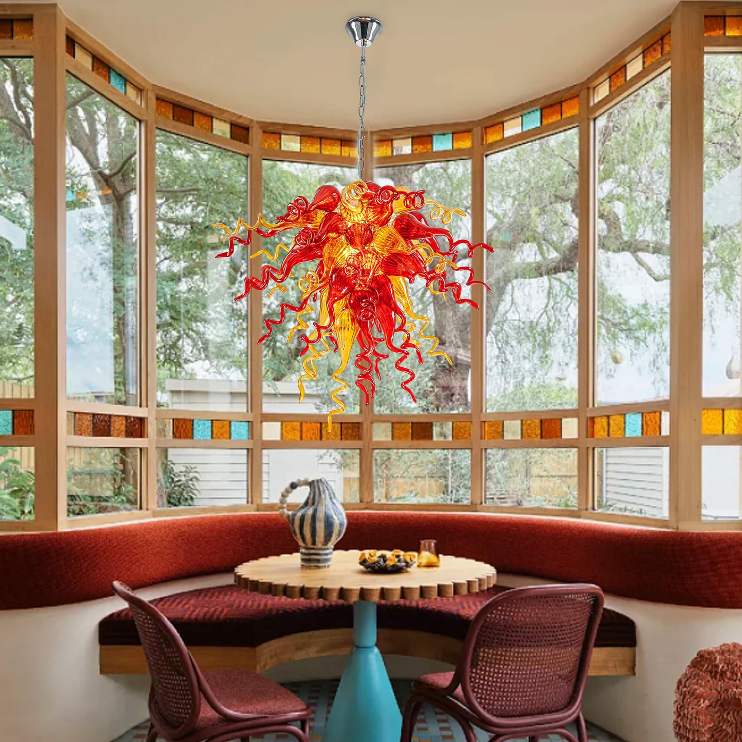 Red and Yellow Hand Blown Art Glass Chandelier in a cozy breakfast nook with a large bay window and stained glass detail.
