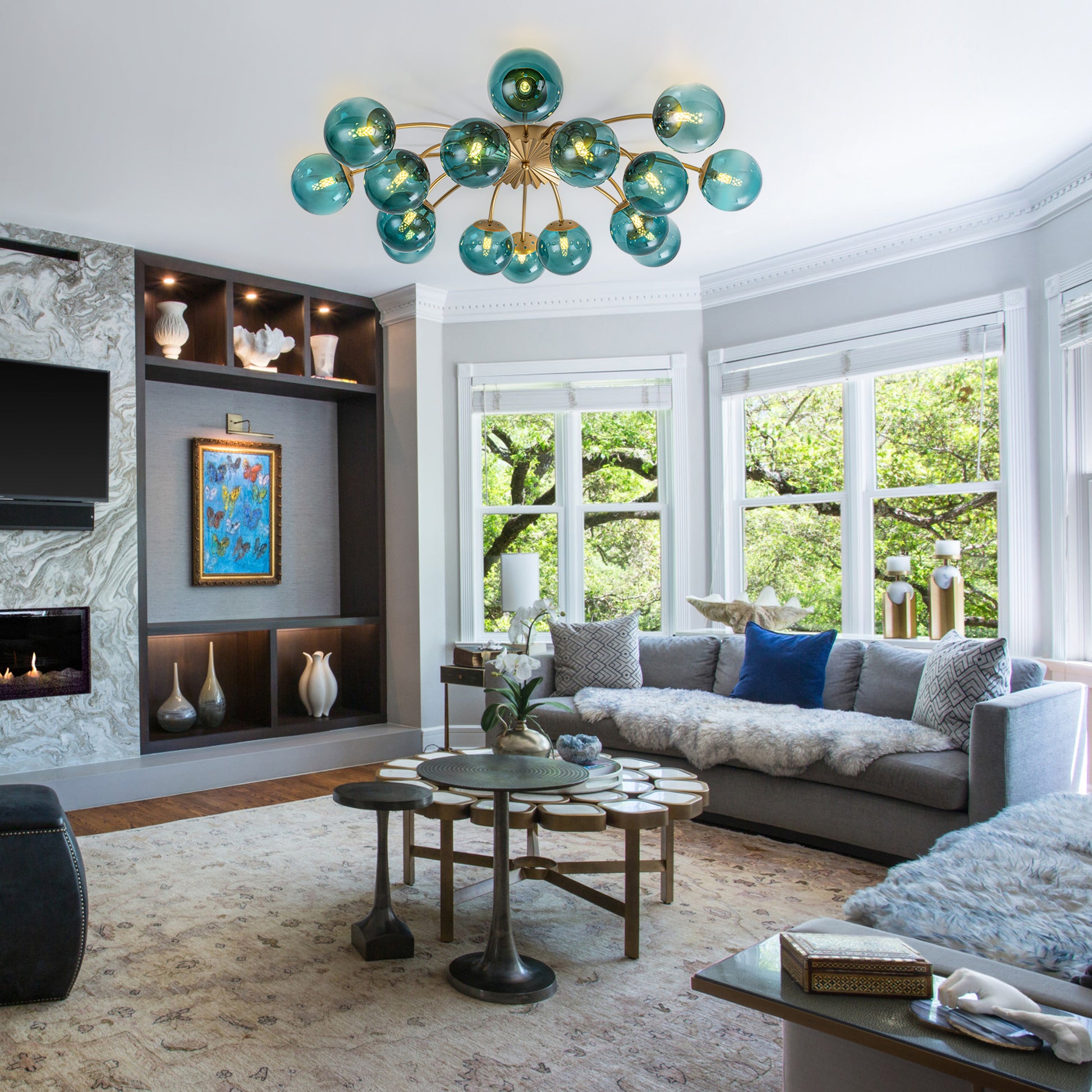 16-Light teal glass bubble globe ceiling light in sunlit living room with green outdoor view.