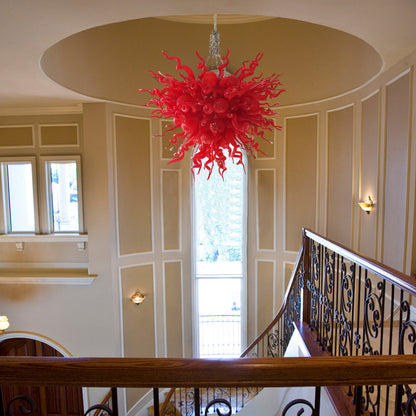 Red abstract hand blown glass sculpture functioning as a grand art chandelier in a luxury home.