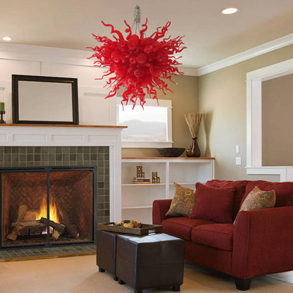 Red hand blown art glass chandelier illuminating a cozy living room with a coral-colored sofa.