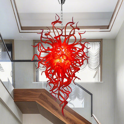 Red sculptural hand blown glass chandelier in an entryway over a modern wooden staircase.