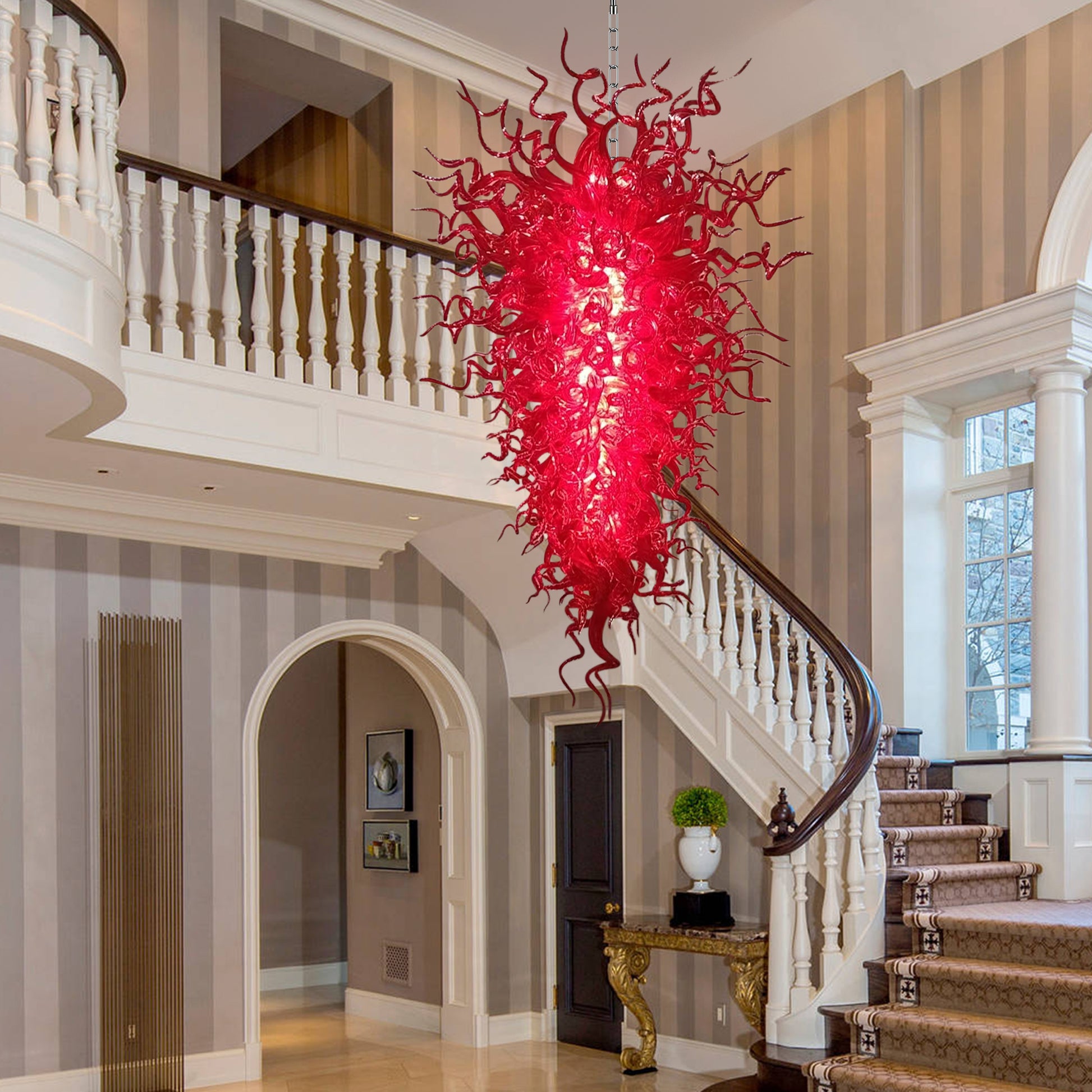 Grand staircase landing featuring a dramatic red Chihuly-style murano blown glass chandelier as a brilliant central light.