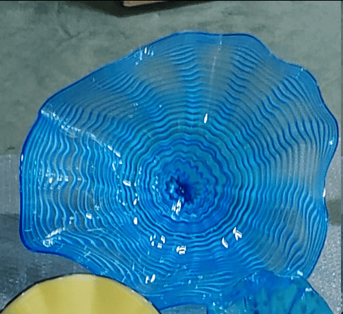 Blue glass plate with wavy design on a gray surface