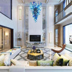 Striking blue blown glass chandelier in a modern double-height living room with a TV wall and balcony.