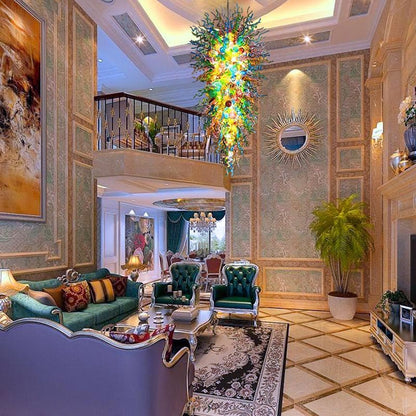 Luxurious double-height hotel lobby with ornate gold detailing, featuring the giant colorful glass chandelier as a grand central masterpiece above a plush lounge area.