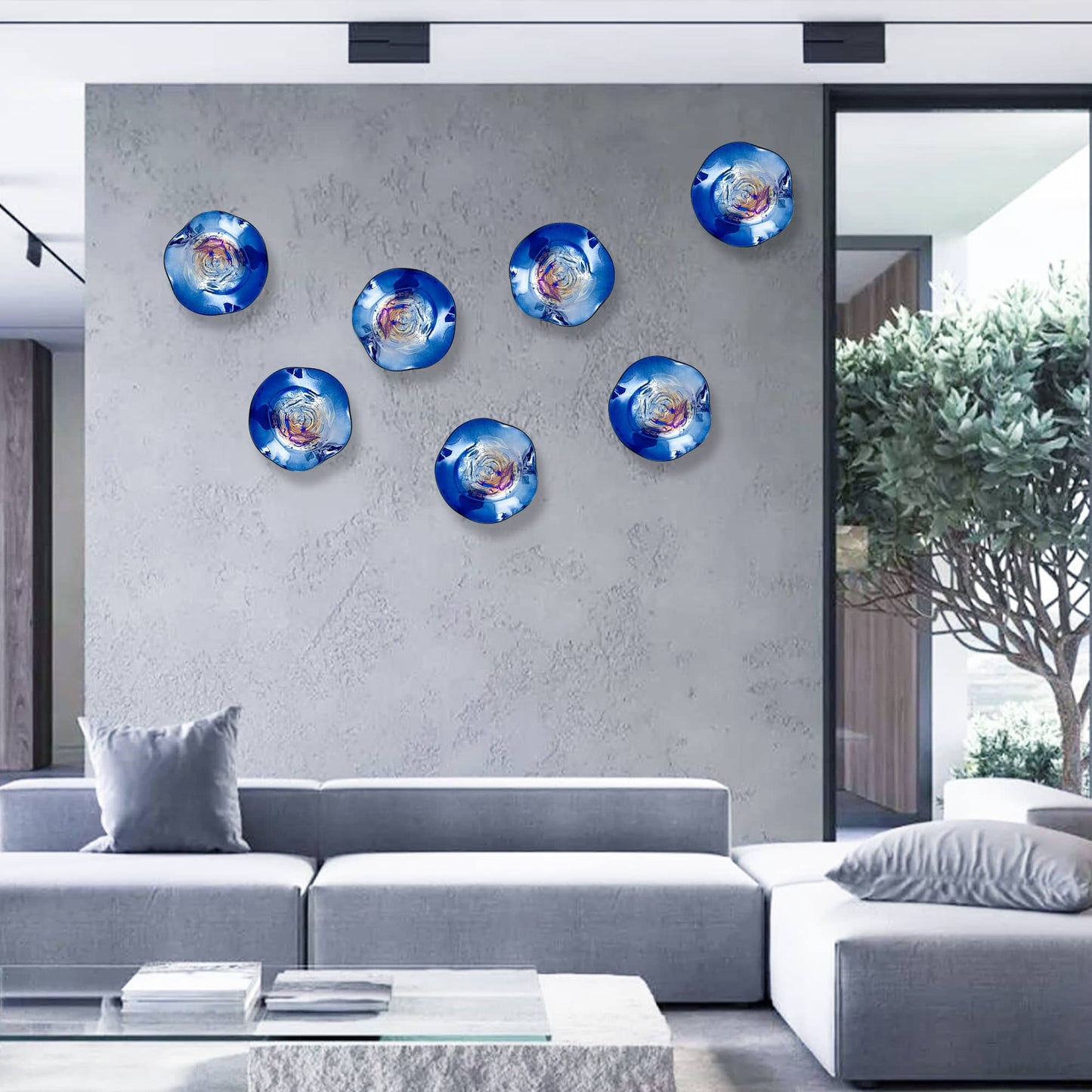 Six deep blue iridescent glass plates creating a custom wall art installation in a contemporary living room.