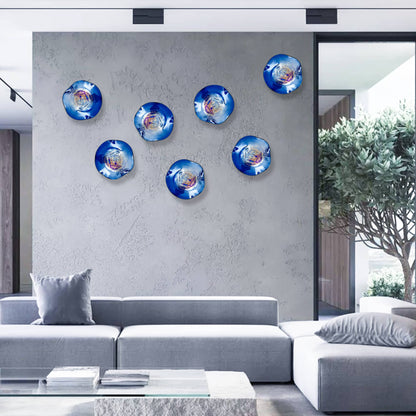 Six deep blue iridescent glass plates creating a custom wall art installation in a contemporary living room.