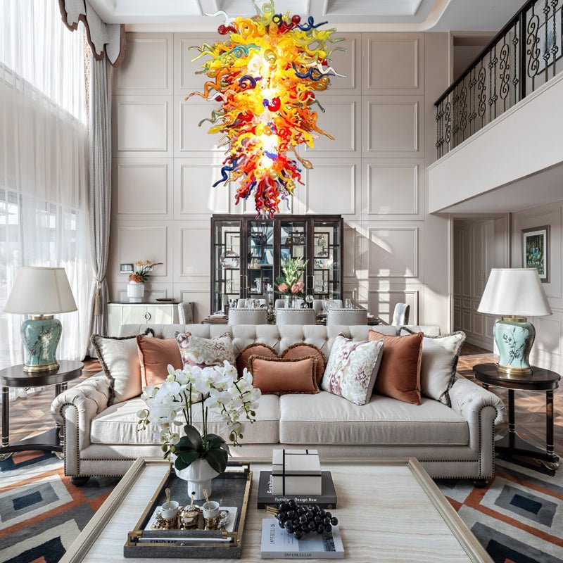 Luxury modern living room with high ceilings, showing the colorful glass art chandelier as a central focal point above the seating area.