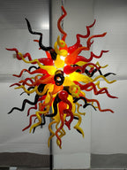 Eternal Flame blown glass chandelier featuring a dense sunburst of red, yellow, and black spiral glass tendrils lit from within.
