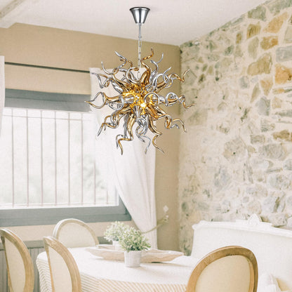 Hand-blown gold and silver art glass chandelier providing a warm focal point over a modern dining table in a textured stone-walled dining room.