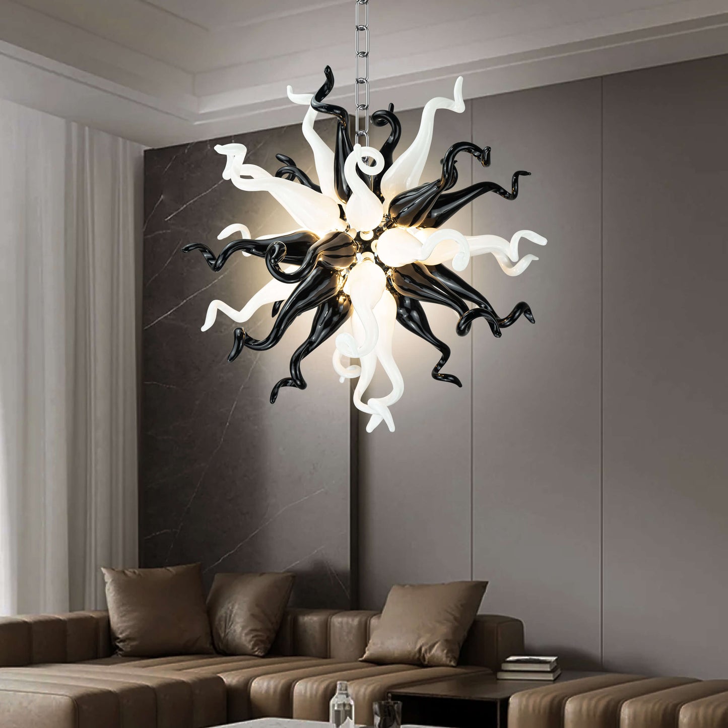 Sculptural monochrome blown glass pendant light in a minimalist room with grey walls and artistic furniture.