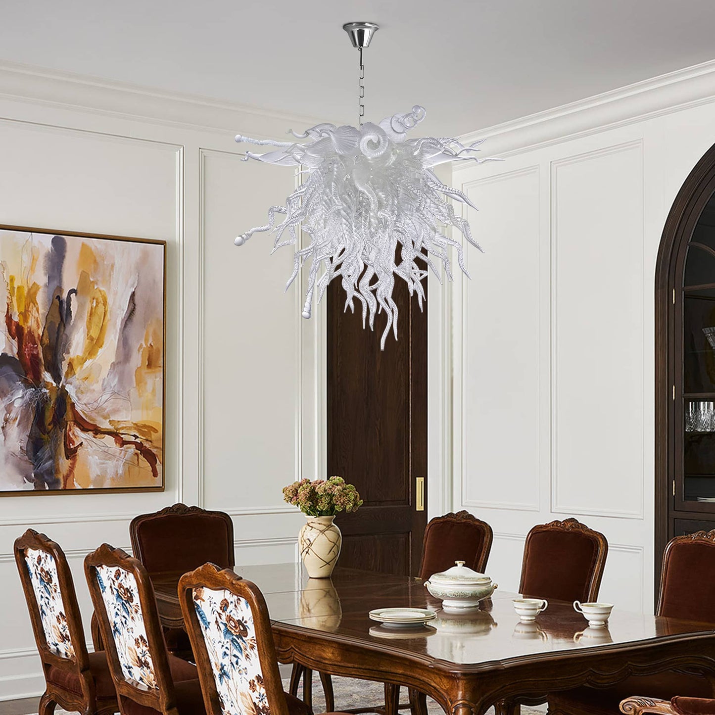 Dramatic clear hand-blown glass chandelier as a grand focal point over a long formal dining table.