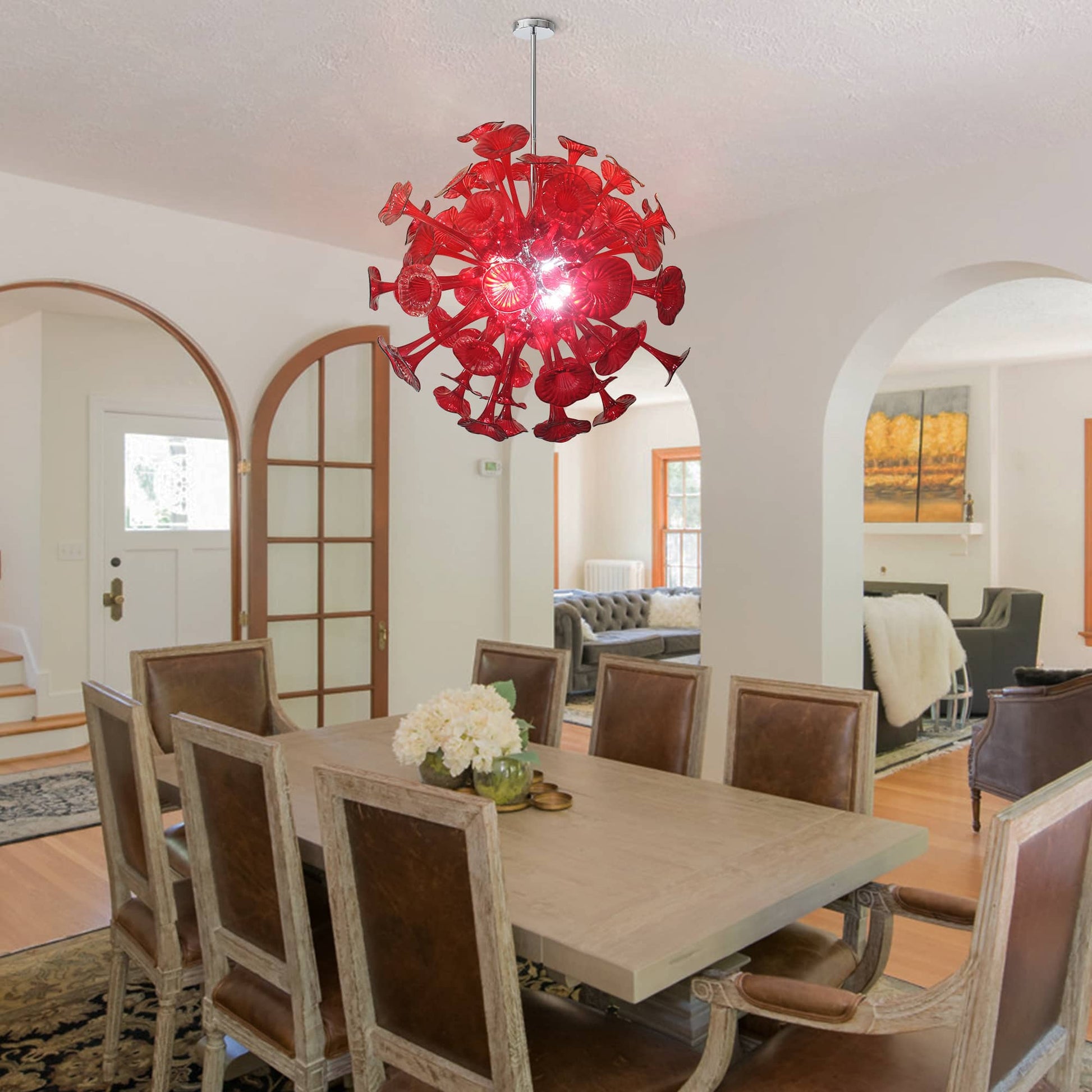 Large red floral glass chandelier hanging in an elegant formal dining room with arched doorways and classic furniture.
