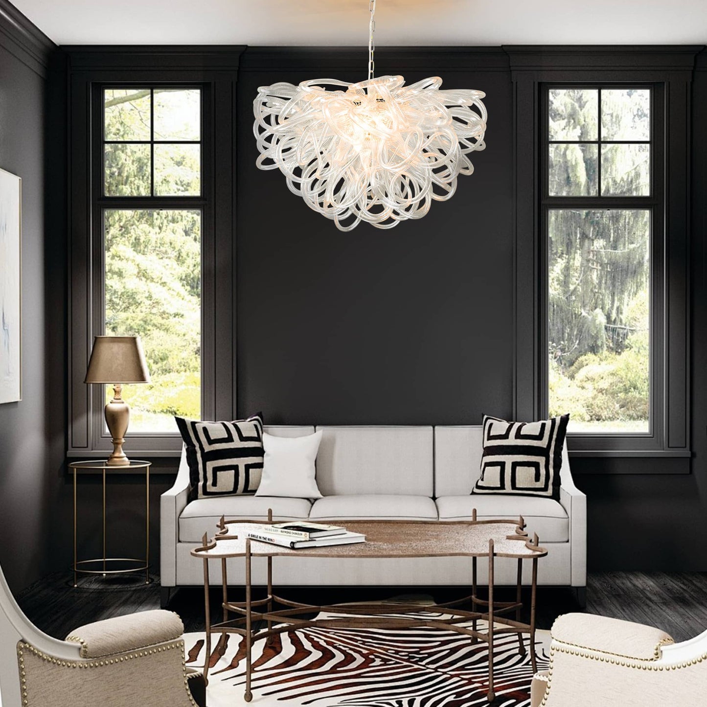 Chic white sofa living area contrasted with a brilliant clear glass chandelier against a black wall.