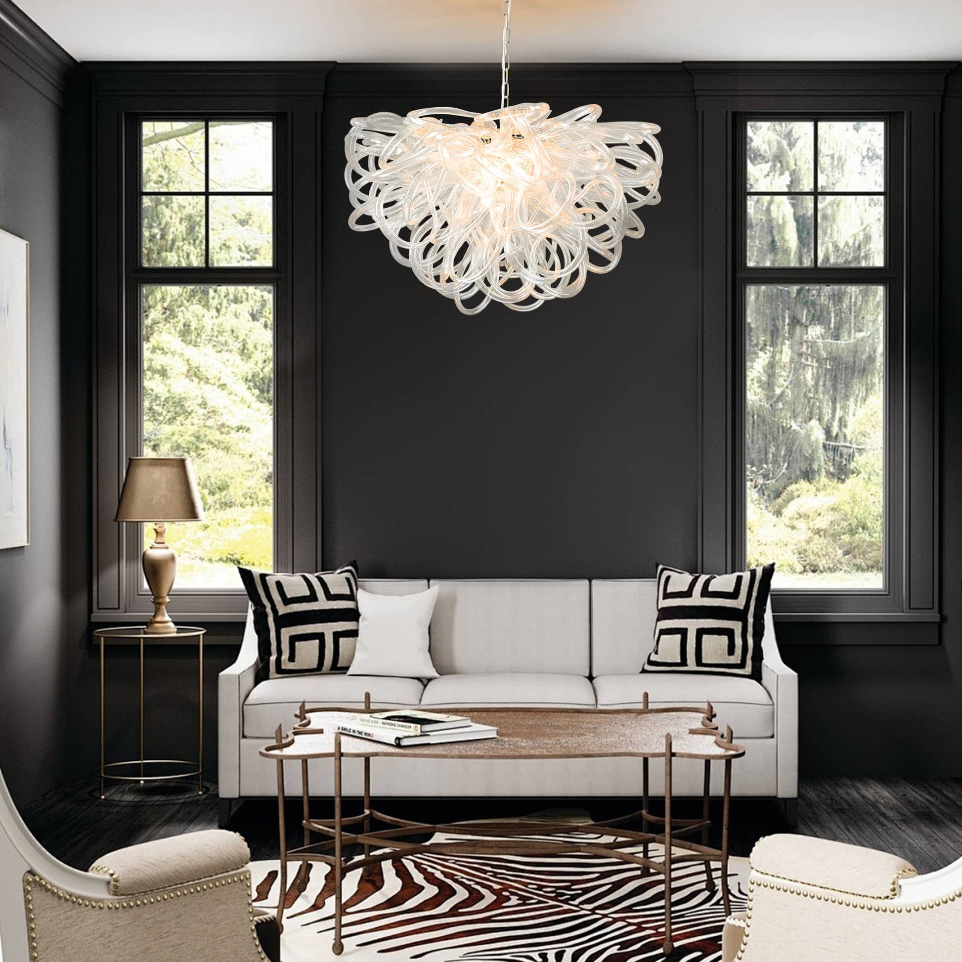 Chic white sofa living area contrasted with a brilliant clear glass chandelier against a black wall.