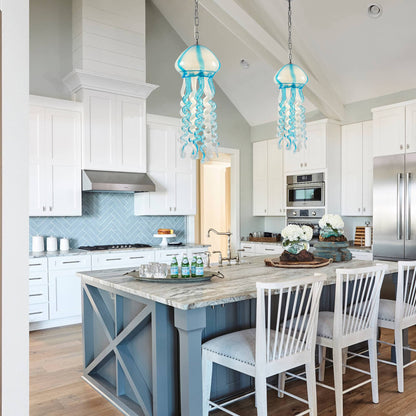 Cluster of two jellyfish glass pendant lights over a white kitchen island with blue cabinetry.