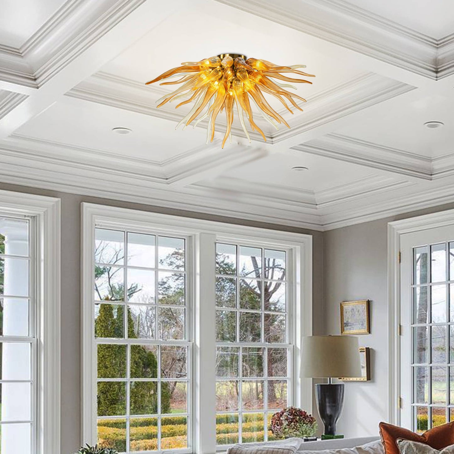 Elegant master bedroom with a tray ceiling and grey bedding, centered by a vibrant orange glass sunburst light fixture.