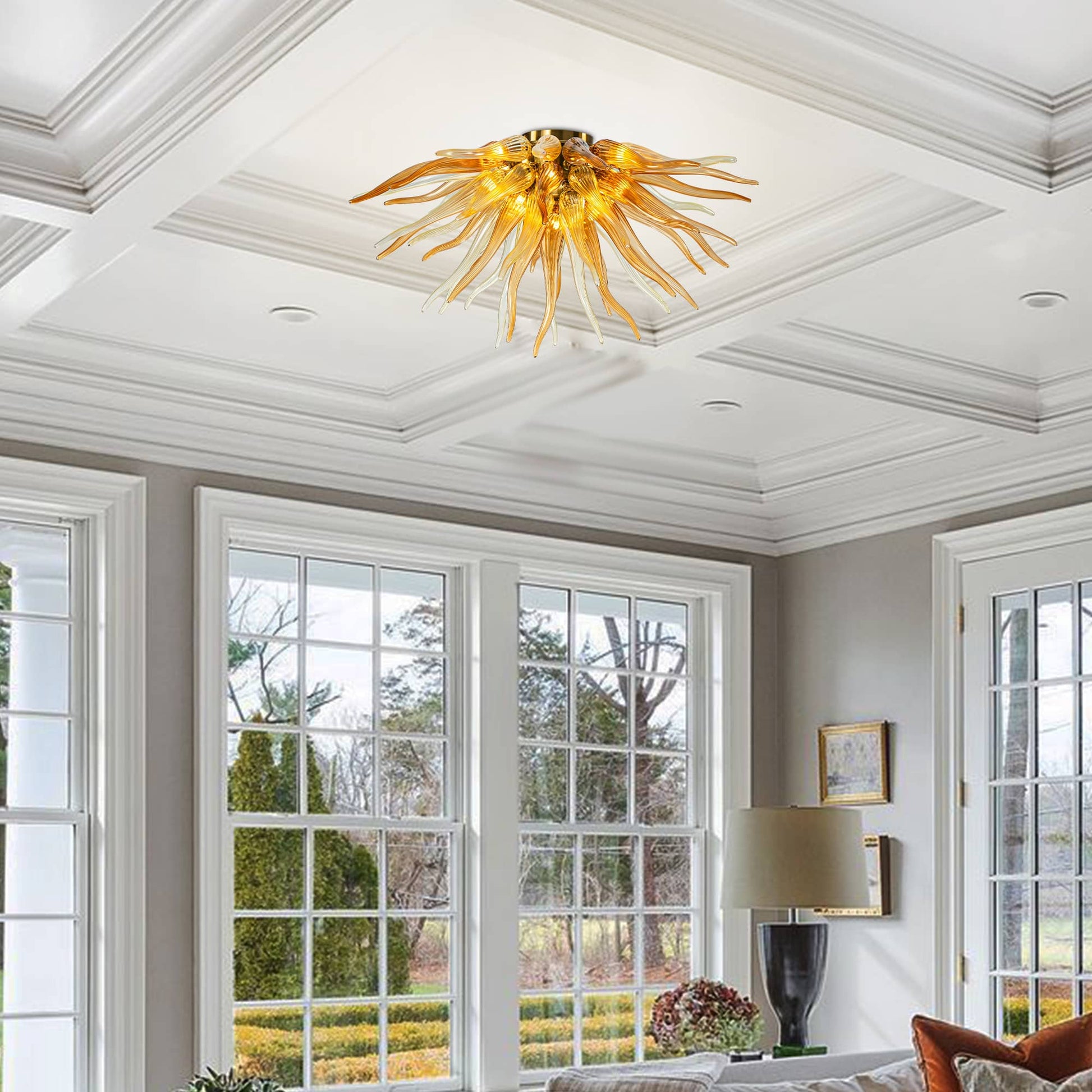 Elegant master bedroom with a tray ceiling and grey bedding, centered by a vibrant orange glass sunburst light fixture.