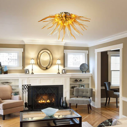 A cozy living room with a stone fireplace and large windows, illuminated by a warm amber glass starburst chandelier.