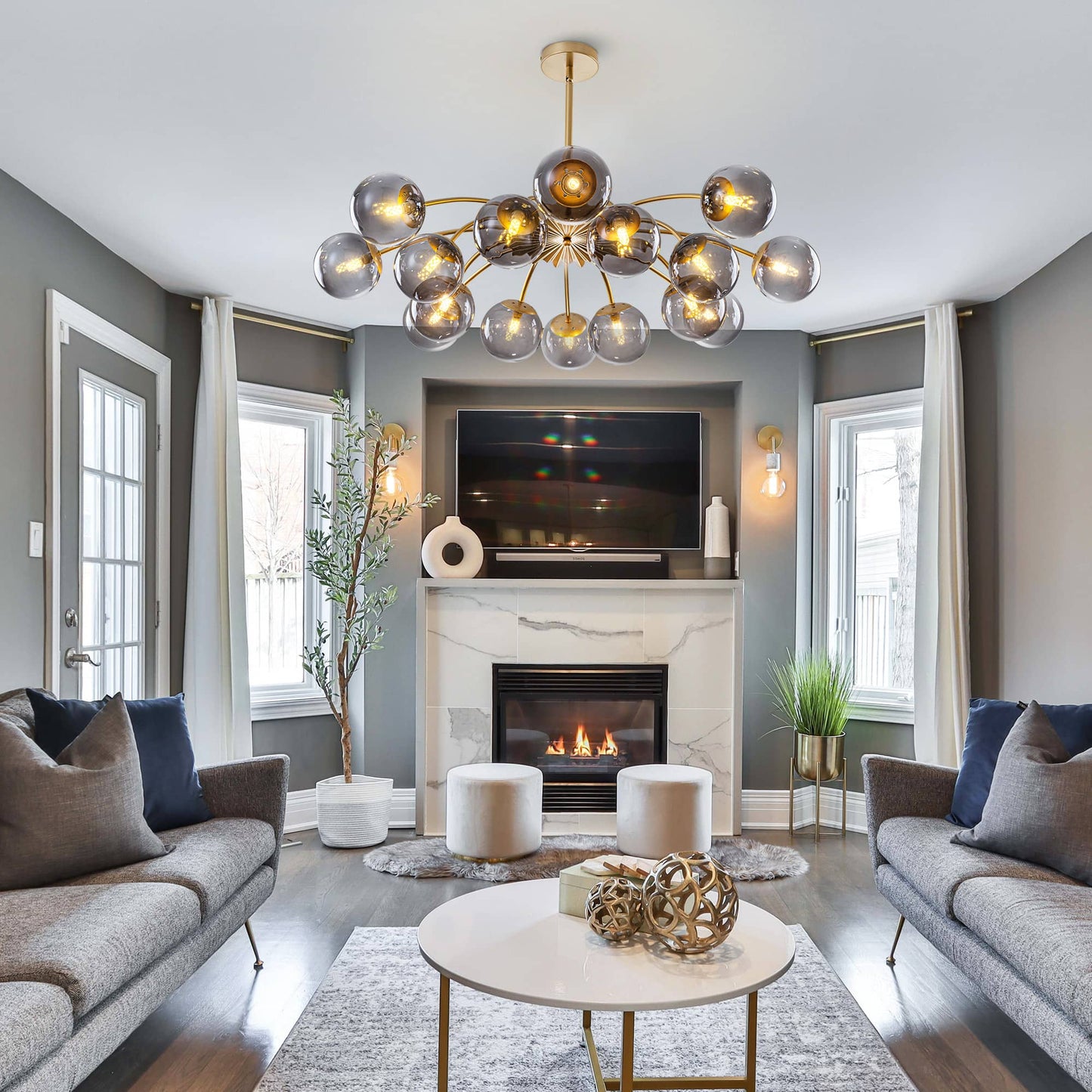 Modern living room with a multi-arms smoky glass balls chandelier, fireplace, and gray sofas.