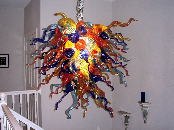 Detailed view of a vibrant Murano style blown glass chandelier with multicolored curly glass tendrils in a residential setting.