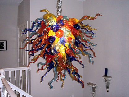 Detailed view of a vibrant Murano style blown glass chandelier with multicolored curly glass tendrils in a residential setting.