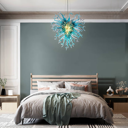 Artisan blue glass chandelier adding a serene oceanic touch above a contemporary upholstered bed.