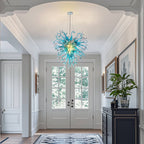 Elegant artisan glass sculpture lighting welcoming guests in a luxury home foyer with high ceilings.