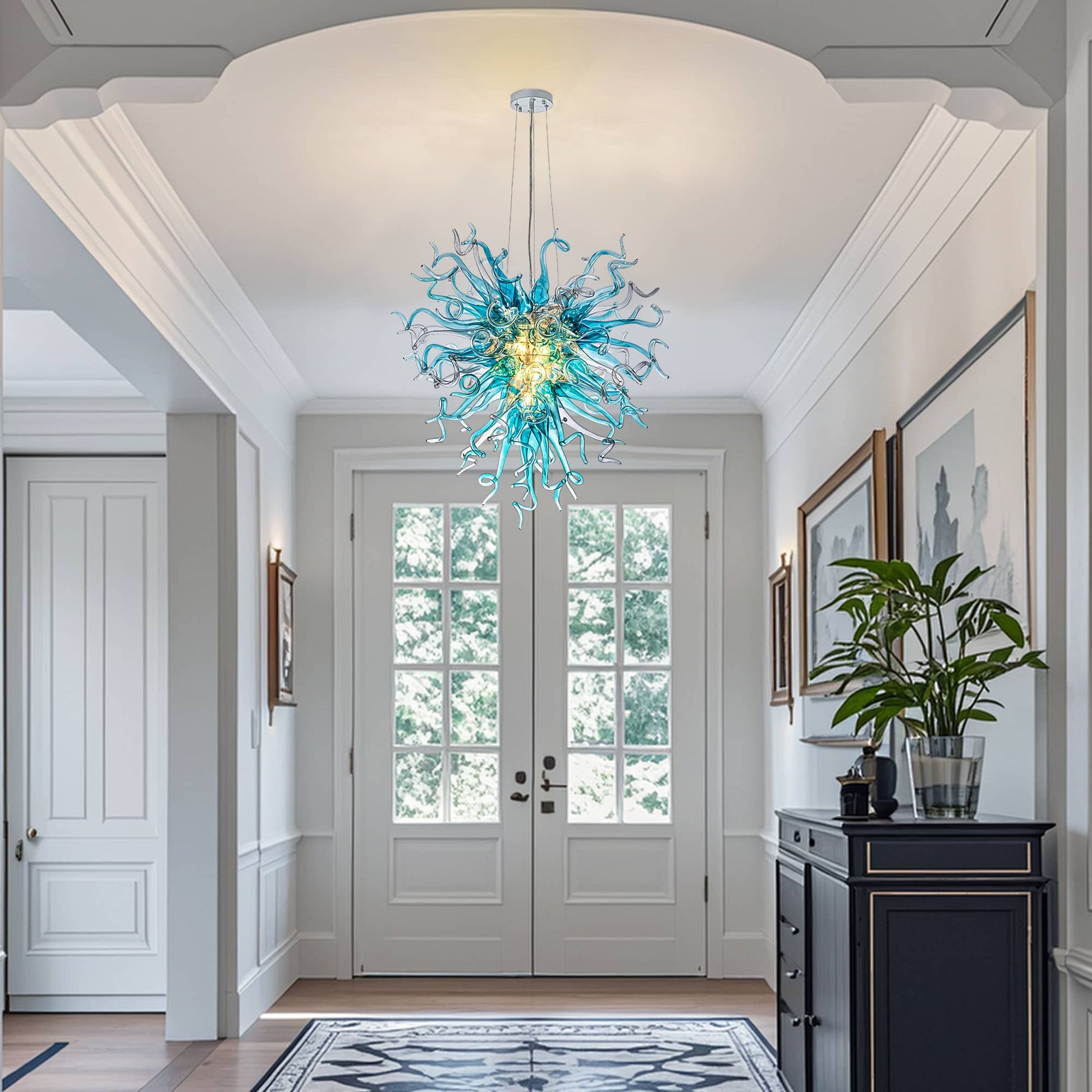 Elegant artisan glass sculpture lighting welcoming guests in a luxury home foyer with high ceilings.