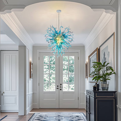 Elegant artisan glass sculpture lighting welcoming guests in a luxury home foyer with high ceilings.