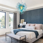 Large blue art glass chandelier providing a striking artistic contrast in a minimalist master bedroom.
