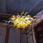High-ceiling interior illuminated by a bright yellow and red sculptural glass chandelier, showcasing its vivid true-to-life colors.