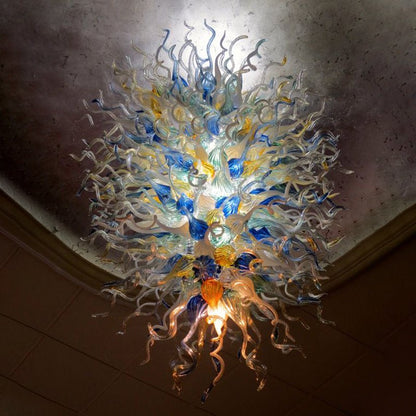 Medium shot of the large-scale glass chandelier showcasing the dense layering of vibrant blue and golden hand-blown glass elements.