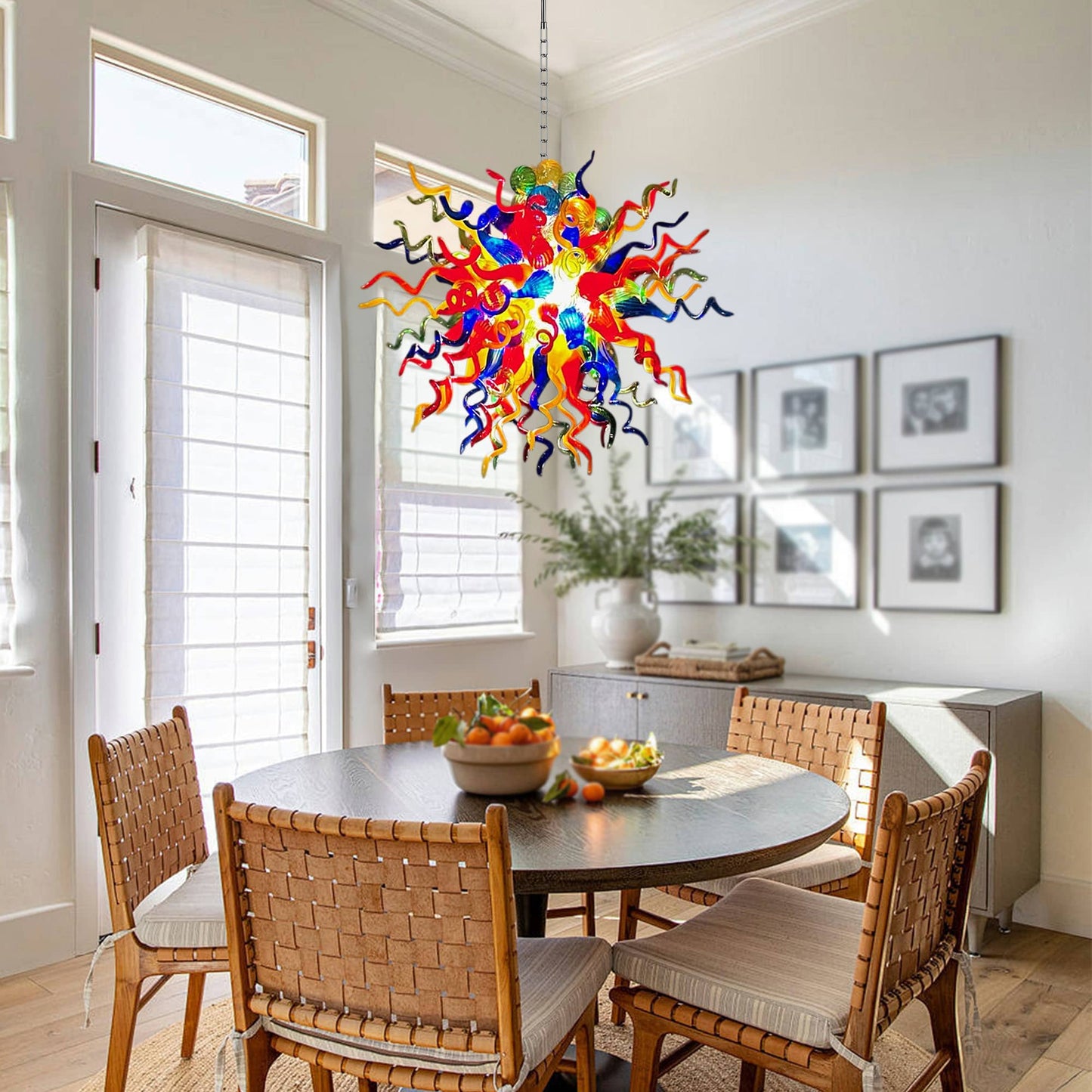 Artisan multicolor blown glass chandelier hanging above a wooden dining table with bohemian rattan chairs.