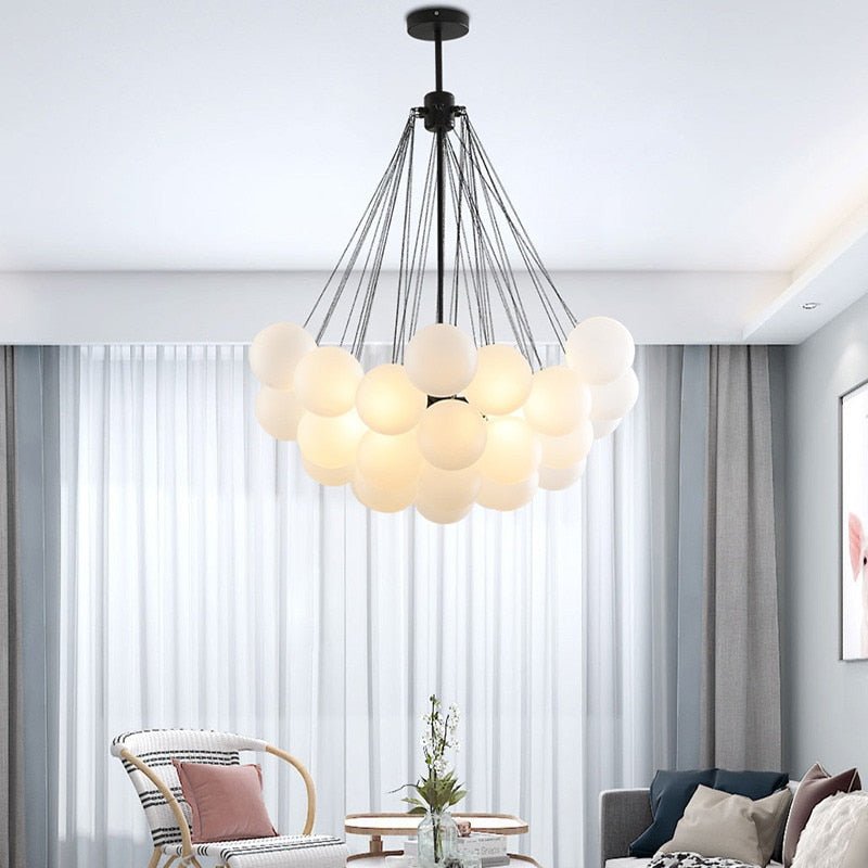 Elegant modern living room with a white frosted glass bubble chandelier centered above a grey sofa.