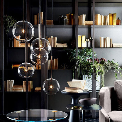 Contemporary home library featuring multiple clear glass bubble pendants hung at varied heights in front of a dark bookshelf.